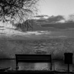 Imagem em preto em branco de um banco em frente ao mar. Representa o tema do artigo - o suicídio de um ateu - da Revista Espírita de 1861